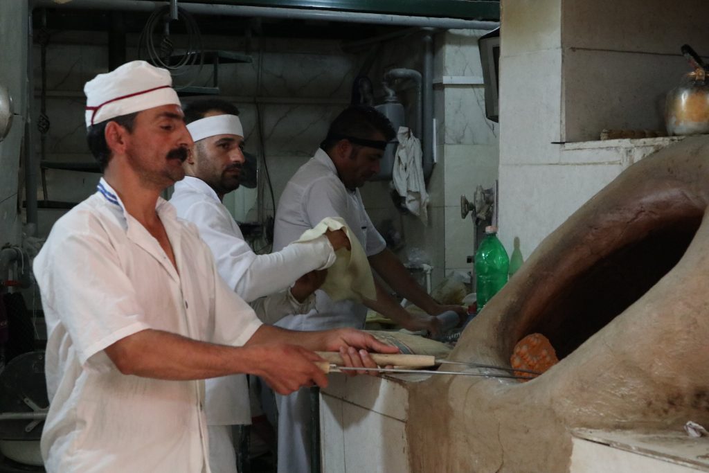 イランの首都テヘランの市場にてナンを焼く男性たち。